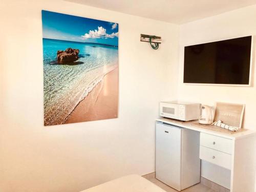 a kitchen with a microwave and a picture of the ocean at A 2 passi dal mare! in Es Pujols