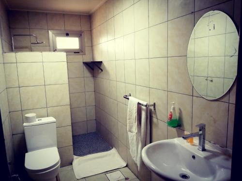 a bathroom with a toilet and a sink and a mirror at La Couronne Suites in Bangui