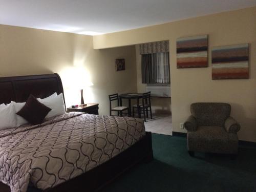 a hotel room with a bed and a chair at Pacer Inn & Suites Motel in Delaware