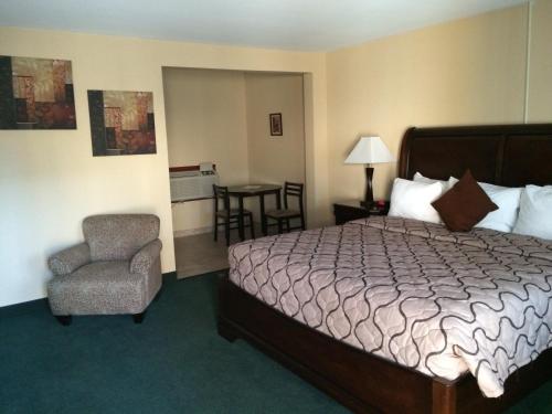 a hotel room with a bed and a chair at Pacer Inn & Suites Motel in Delaware