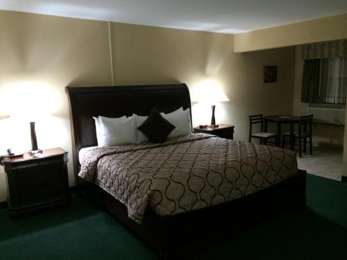 a bedroom with a bed with two lamps and a table at Pacer Inn & Suites Motel in Delaware