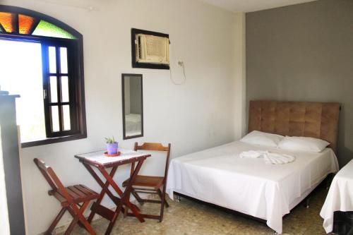 a bedroom with a bed and a table and chairs at Solares de Maricá in Maricá