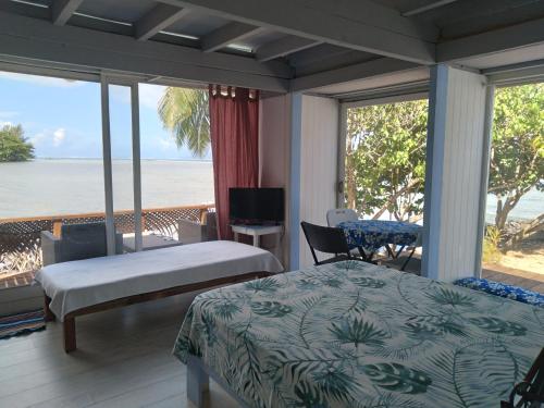 a bedroom with a bed and a view of the ocean at Bungalow blue lagon waterfront in Moorea