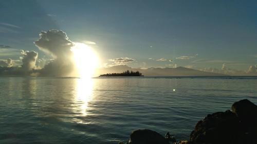 a sun setting over a large body of water at Bungalow les pieds ds l eau, La Maison Bleue in Moorea