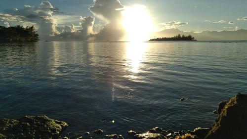 a sun setting over a body of water at Bungalow les pieds ds l eau, La Maison Bleue in Moorea