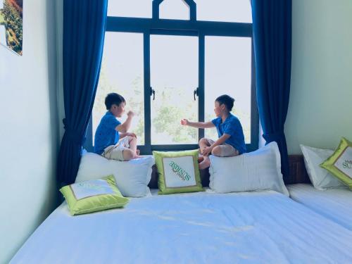 two children sitting on a bed looking out the window at SUNRISE HOTEL in Con Dao