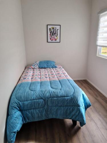 a bed with a blue comforter in a bedroom at Cabañas Alto Volcanes in Puerto Montt