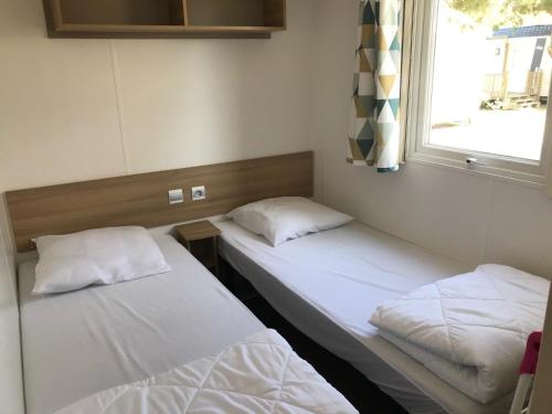 due letti in una stanza con una finestra di Mobil Home camping Mar Estang bord de plage a Canet-en-Roussillon
