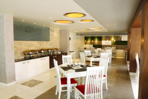 a dining room with white tables and white chairs at Miles Inn Hotel in Hassan