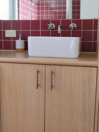 um lavatório branco em cima de um balcão de madeira na casa de banho em Sea-Esta @ Inverloch em Inverloch