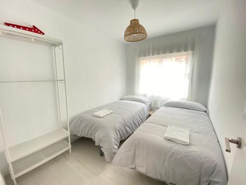 2 Betten in einem weißen Zimmer mit Fenster in der Unterkunft NUEVO, con vistas al mar y a 70 metros de la playa in Cullera