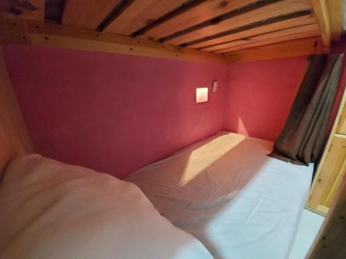 a bed in a small room with a red wall at Hostal el Alebrije in Valle de Bravo