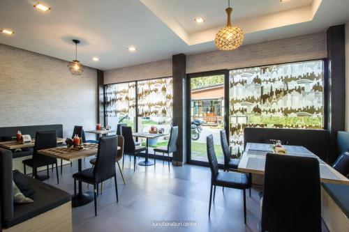 restauracja ze stołami, krzesłami i oknami w obiekcie Makan Resort w mieście Kanchanaburi