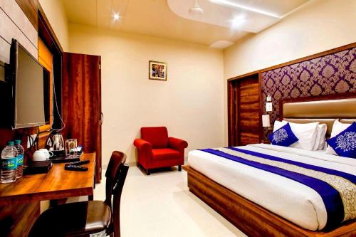 a bedroom with a bed and a desk and a red chair at Hotel Spiti in Mathura