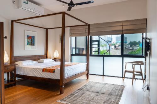 a bedroom with a canopy bed and a large window at Havelock Gardens BnB in Colombo
