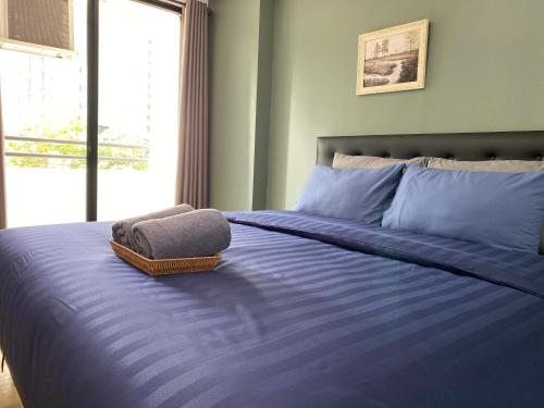 a bed with a blue comforter with a towel on it at Baansuay Rattanathibet Apartment in Nonthaburi