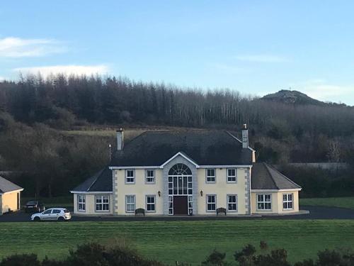 a large white house with a car parked in front of it at Greenmile House, in Kilmeaden