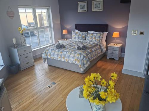 a bedroom with a bed and a table with flowers at Greenmile House, in Kilmeaden