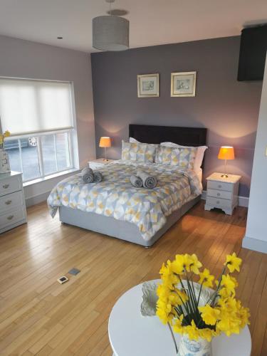 a bedroom with a bed and a table with flowers at Greenmile House, in Kilmeaden