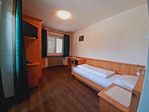 Habitación pequeña con cama y escritorio. en Hotel Pörnbacher, en Valdaora