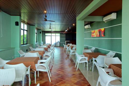 a dining room with tables and white chairs at Park Residency Koyilandi in Quilāndi