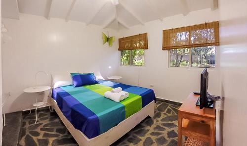 1 dormitorio con 1 cama, TV y ventanas en Bungalow Natura Village, en Sosúa