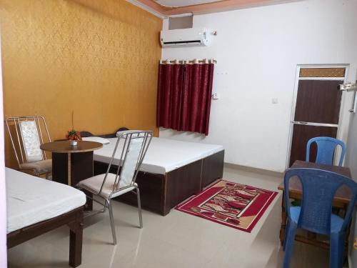 a room with a bed and a table and chairs at vindhyvasini guest house in Kushinagar