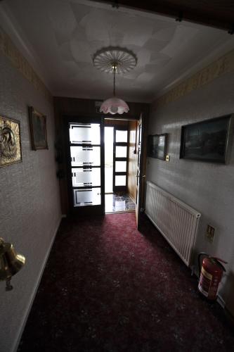 an empty room with a hallway with a door and a red carpet at Sandwick Bay Guest House in Stornoway