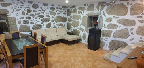 ein Wohnzimmer mit einer Couch und einer Steinwand in der Unterkunft Quinta da Tormenta -14 pessoas- Cabeceiras de Basto 2 casas e piscina privada in Cabeceiras de Basto