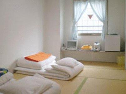 um quarto com três toalhas no chão com uma janela em Ikawa Ryokan em Hiroshima