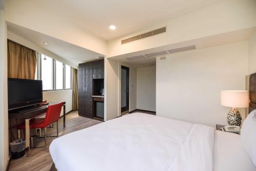 a hotel room with a white bed and a desk at Jih Lih Hotel in Magong