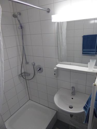 ein weißes Bad mit einer Dusche und einem Waschbecken in der Unterkunft Ferienwohnung Zollernblick in Tübingen