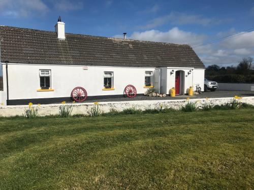 a white house with a red door and a yard at Toddys Cottage & Stables in Cavan