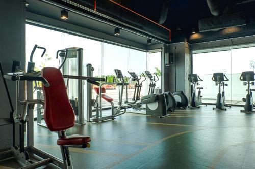 a gym with a lot of cardio equipment and a red chair at The Twin Lotus Hotel in Nakhon Si Thammarat