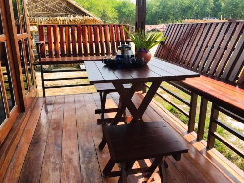 una terrazza in legno con tavolo e panca di ไร่นาบัวหลวง คาเฟ่ & ฟาร์มสเตย์ RaiNa BuaLuang Cafe & Farm Stay a Ban Na No