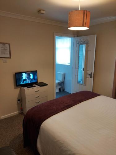 a bedroom with a bed and a flat screen tv at LegenDerry B&B in Derry Londonderry