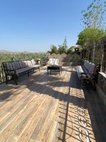 two benches and a table on a wooden deck at UAE farm in Qūr