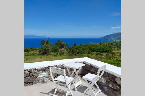 a table and chairs sitting on top of a stone wall at Fish House 3 in Prainha de Cima