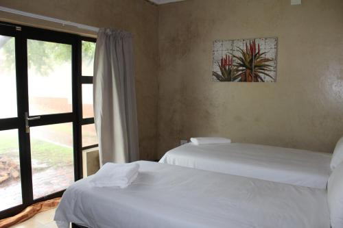 two beds in a room with a window at Euphoria Self Catering Home in Naboomspruit