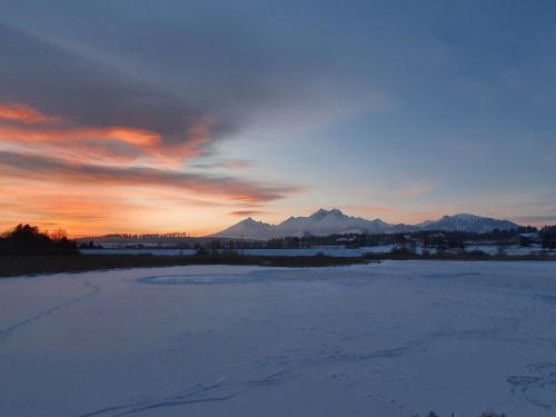 a sunset over a snowy field with mountains in the background at Chatka Panorama in Mlynčeky