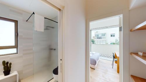 uma casa de banho com um chuveiro e uma porta de vidro em Authentic 3BR Penthouse in Ben Gurion by HolyGuest em Tel Aviv