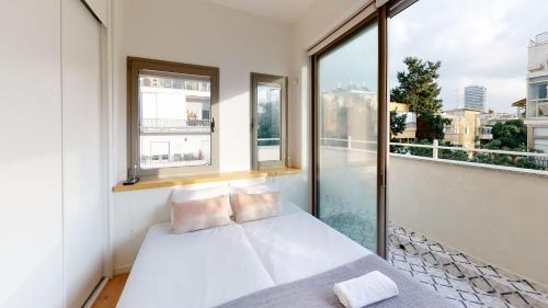 um quarto com uma cama e uma grande janela em Authentic 3BR Penthouse in Ben Gurion by HolyGuest em Tel Aviv
