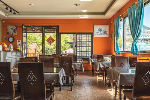 a dining room with tables and chairs and orange walls at Hua Mu Xing Jing B&B in Renai