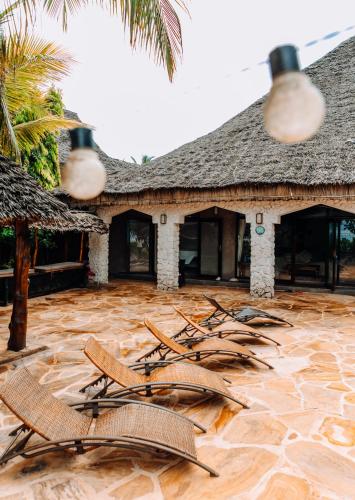 a group of chairs on a patio in front of a building at Tamani Villas in Matemwe