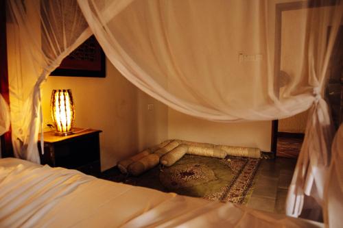 a bedroom with a bed with curtains and a lamp at Tamani Villas in Matemwe
