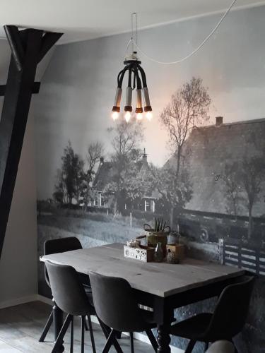 a dining room table with chairs and a painting on the wall at De Bedstee in Holwerd