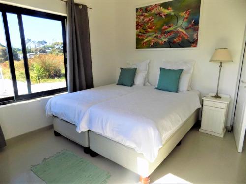 1 dormitorio con 1 cama y ventana grande en Green Goose self catering villa with pool, en Plettenberg Bay