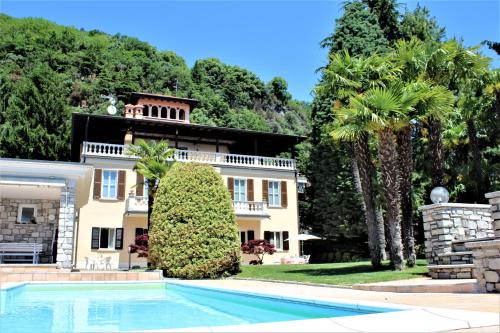 una casa grande con piscina frente a ella en Palazzina GiardinoLago, en Gravedona