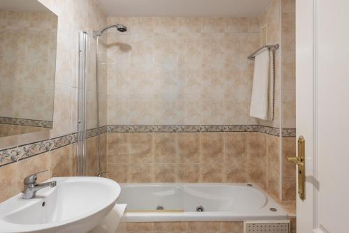Un baño con bañera blanca y lavabo. en DANA II Eurogolf, vistas, wifi, piscina y parking, en Benalmádena