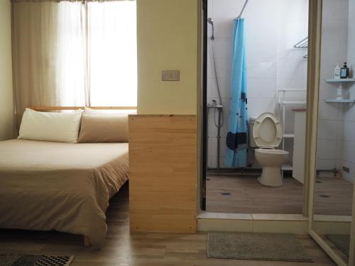 a bedroom with a bed and a bathroom with a toilet at Green Island Oceanrelier依海公寓 in Green Island
